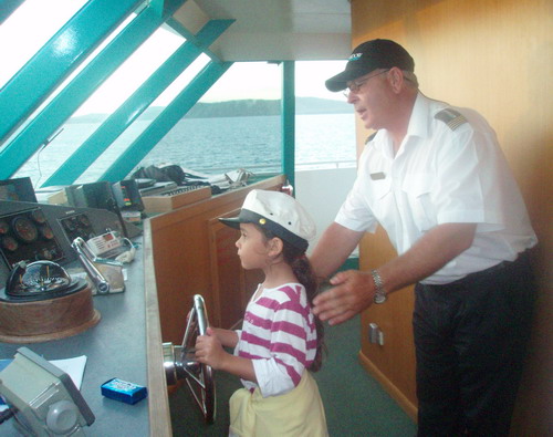 My daughter steering the Moonshadow cruise ship with Captain Troy on Nelson Bay